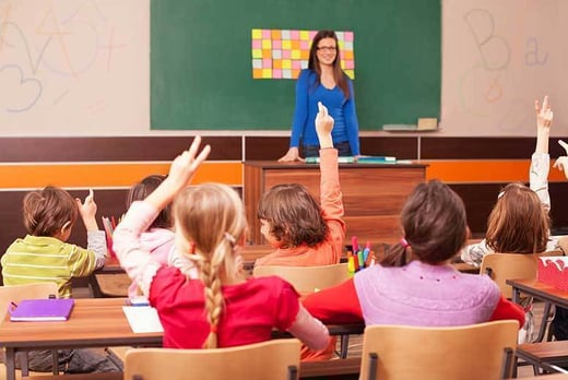 Pupils in a classroom raising their hand to answer a question from the teacher